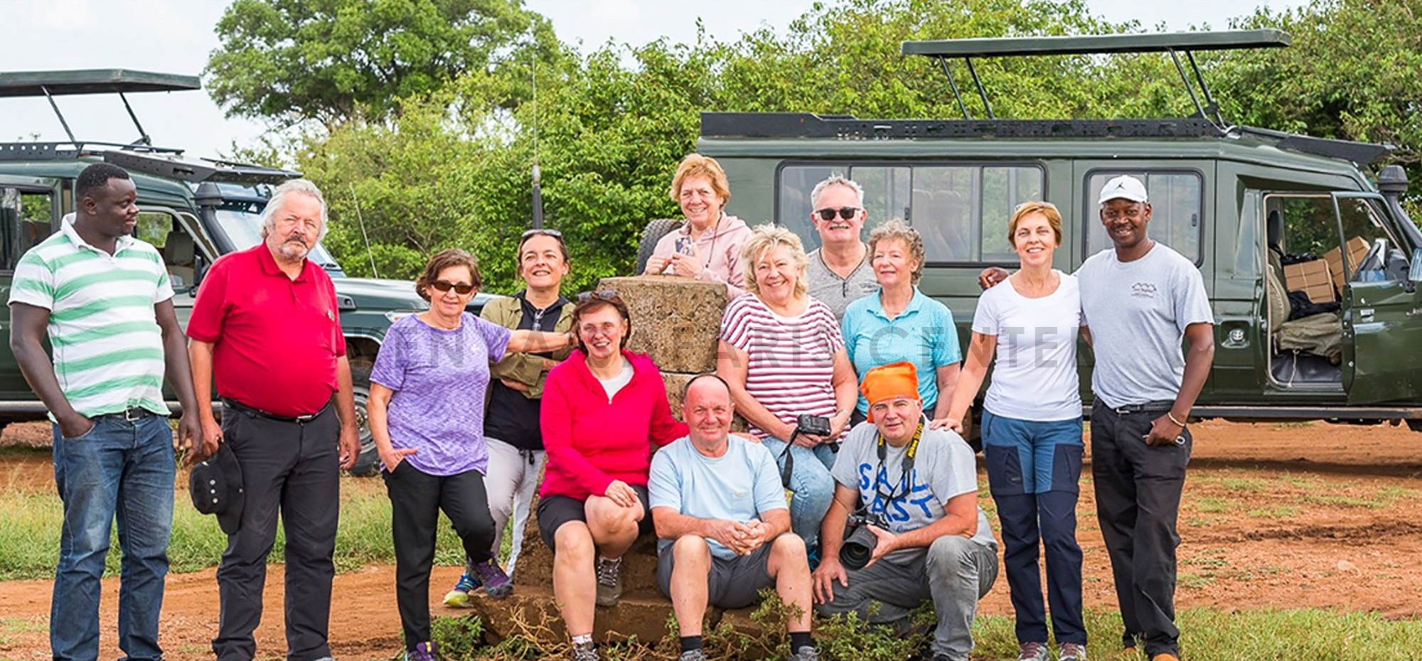Guests and driver-guides posing in front of two safari Land Cruisers