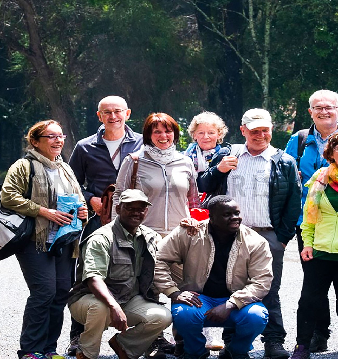 Zwei Fahrer-Guides des Kenya Safari Centre hocken vor ihren Gästen neben den Safari-Fahrzeugen